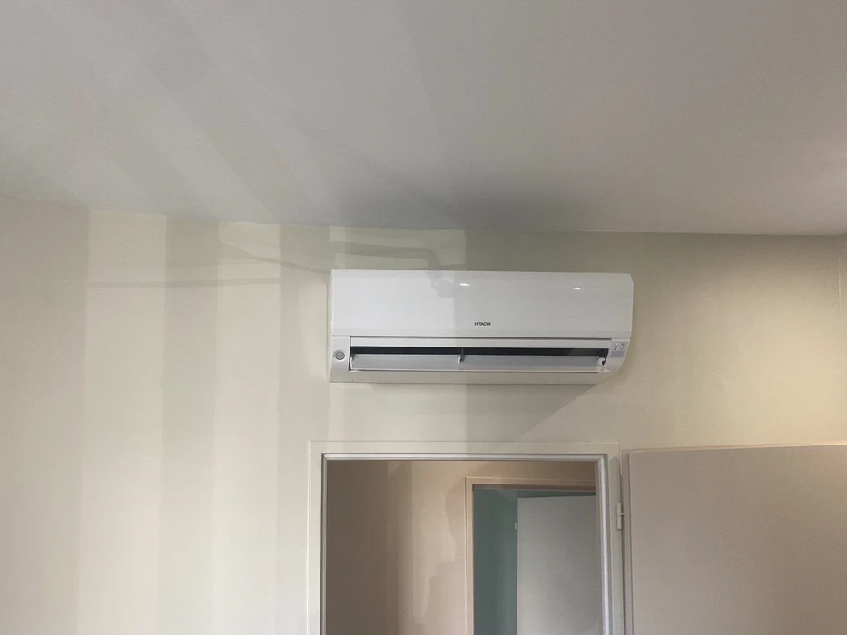 Extérieur d'un bâtiment avec installation de climatisation composée de deux unités extérieures Mitsubishi Electric City Multi montées sur dalle béton contre un mur beige