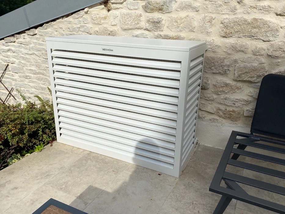 Extérieur résidentiel avec unité de climatisation Hitachi installée sur dalle béton devant maison crépi beige