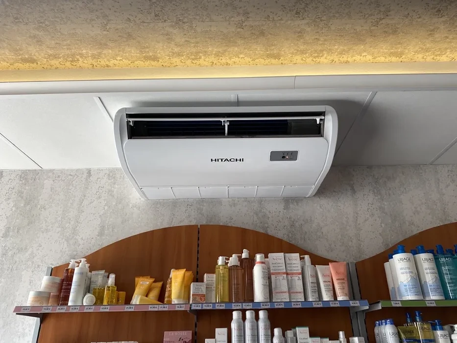 Extérieur d'un bâtiment avec installation de climatisation composée de deux unités extérieures Mitsubishi Electric City Multi montées sur dalle béton contre un mur beige